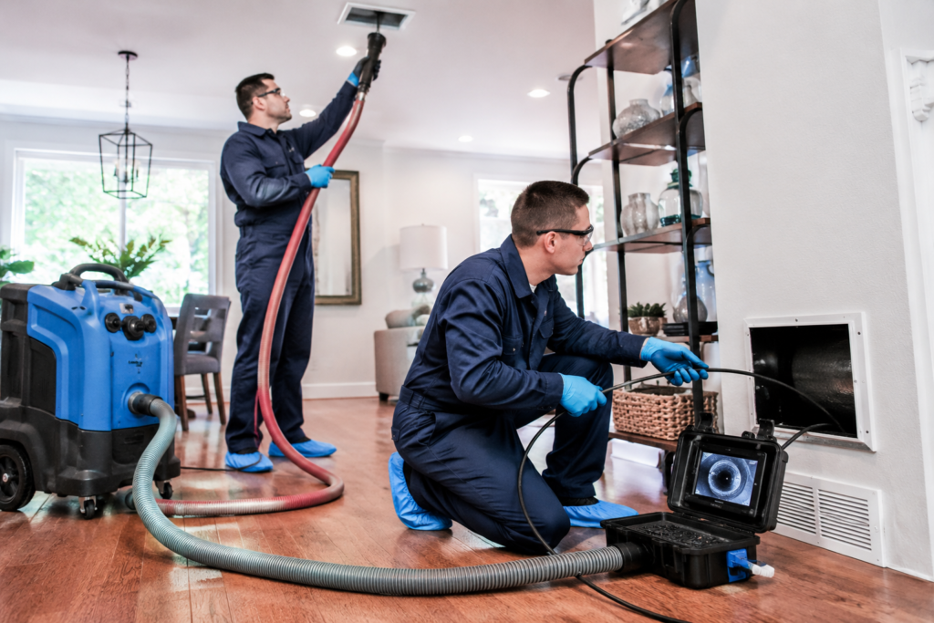 Professional air duct cleaning technicians using HEPA vacuum equipment to clean HVAC ducts in a residential home in Toledo, OH.